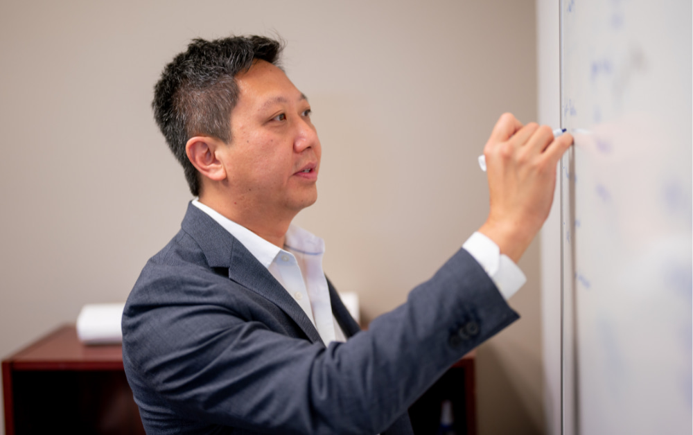 Paul Wang writing on a white board - market