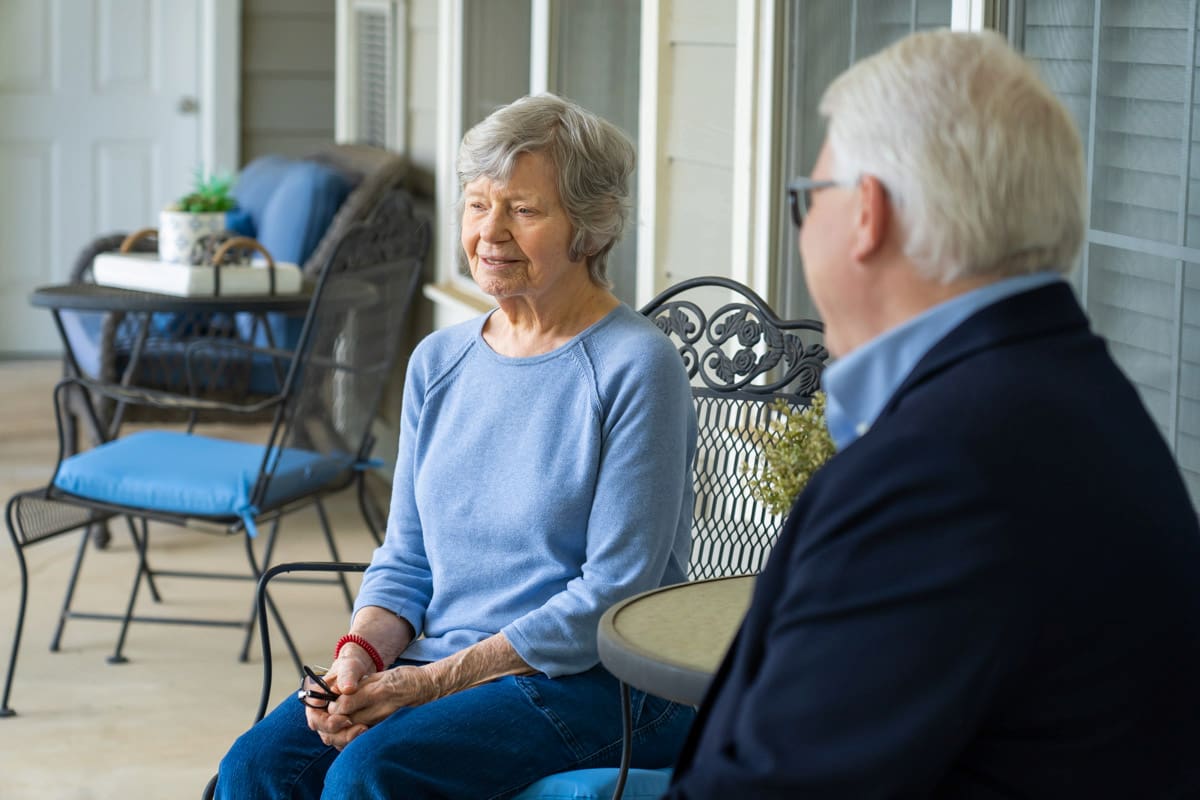 An elderly resident enjoys sitting outside on a patio