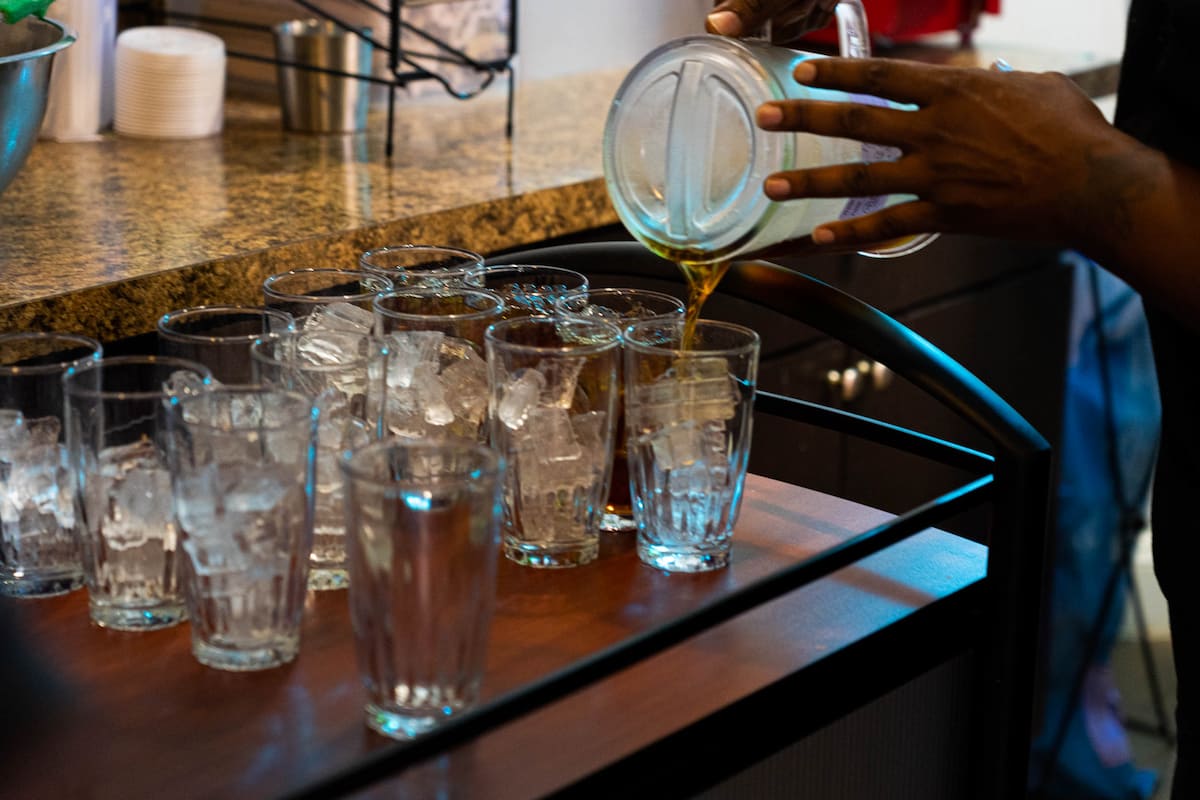 A server pours water into glasses filled with ice